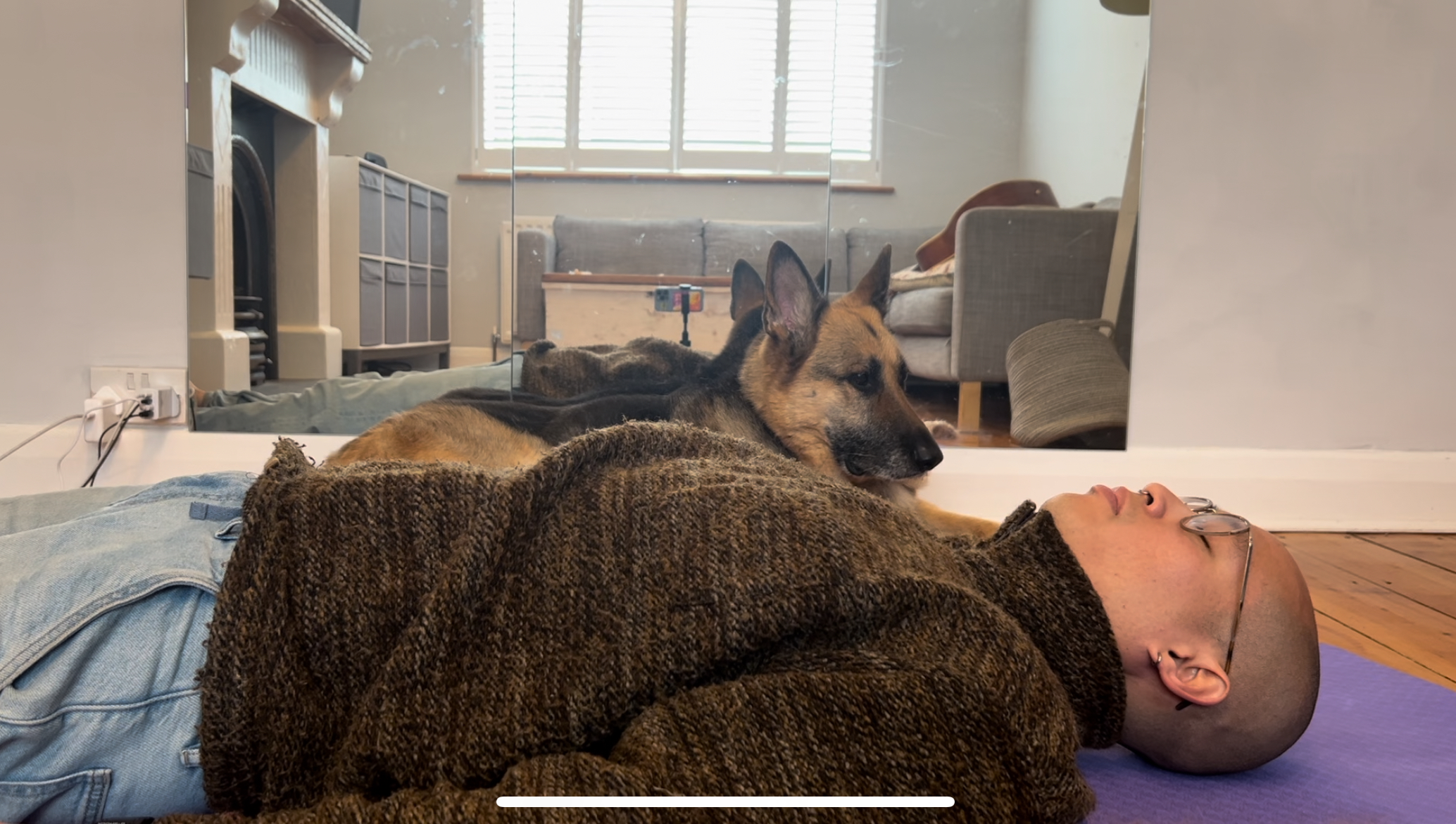 Me laying on my back, comfortably resting on a lavender Pilates mat. Metric (German Shepherd) in background, keeping me company